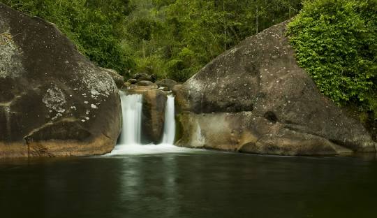 Cachoeira com pedras e água ao fundo Descrição gerada automaticamente com confiança média