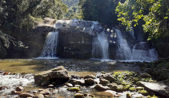 Cachoeira com pedras e água ao fundo Descrição gerada automaticamente