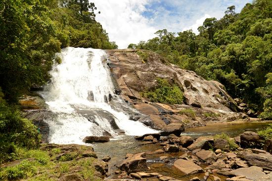 Cachoeira com pedras e água ao fundo Descrição gerada automaticamente