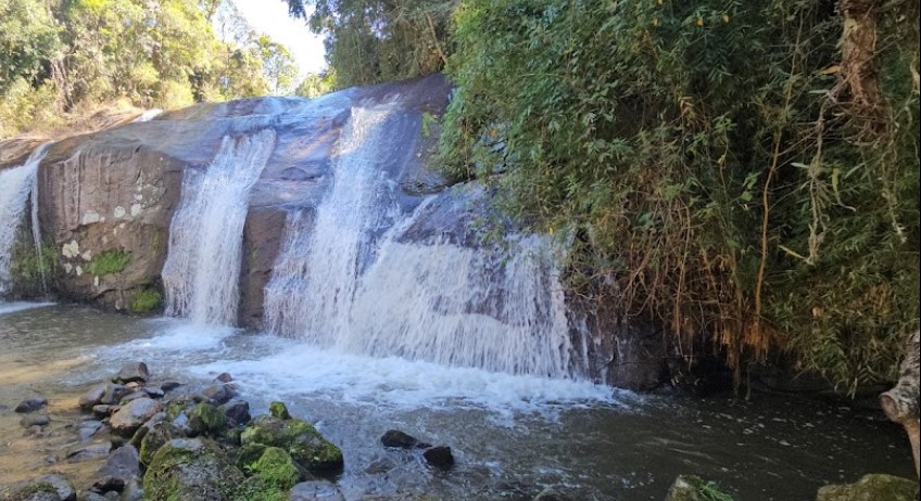 Cachoeira com pedras e água ao fundo Descrição gerada automaticamente