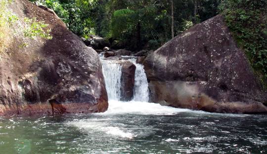 Cachoeira com pedras e água ao fundo Descrição gerada automaticamente com confiança média