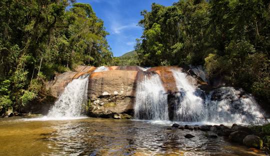 Cachoeira no meio de um rio Descrição gerada automaticamente com confiança média