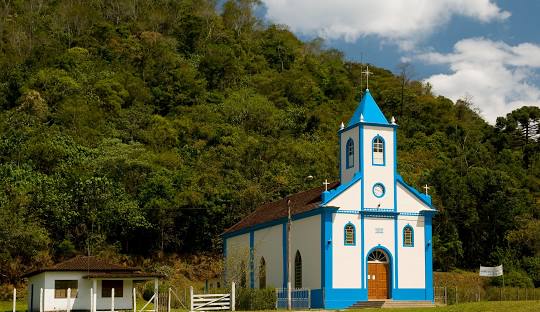 Igreja com torre alta ao fundo Descrição gerada automaticamente