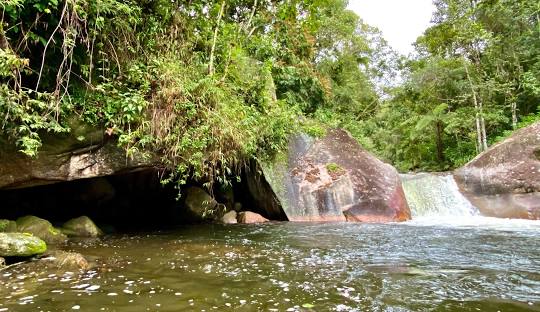 Rio com pedras e água ao fundo Descrição gerada automaticamente