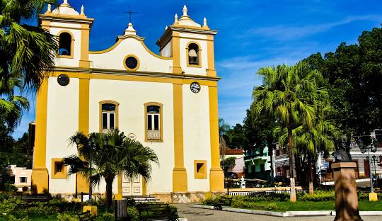 Torre alta em frente a igreja Descrição gerada automaticamente com confiança média