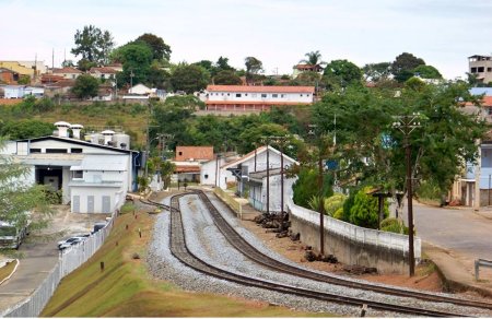 Trem em movimento sobre trilhos e árvores ao fundo Descrição gerada automaticamente
